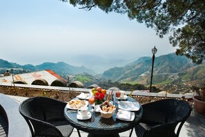 Une table dressée pour le petit-déjeuner, avec une vue imprenable sur les montagnes.
