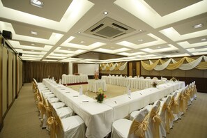 A conference room with long tables, white tablecloths, and chairs with gold sashes. - Hotel Express Towers (Vadodara)