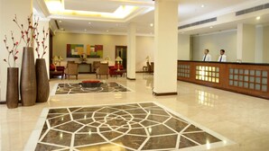 A spacious lobby with a reception desk, seating area, and decorative vases. - Hotel Express Towers (Vadodara)