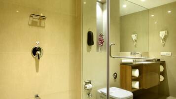 A modern bathroom with a glass shower enclosure, a toilet, and a sink with a mirror.