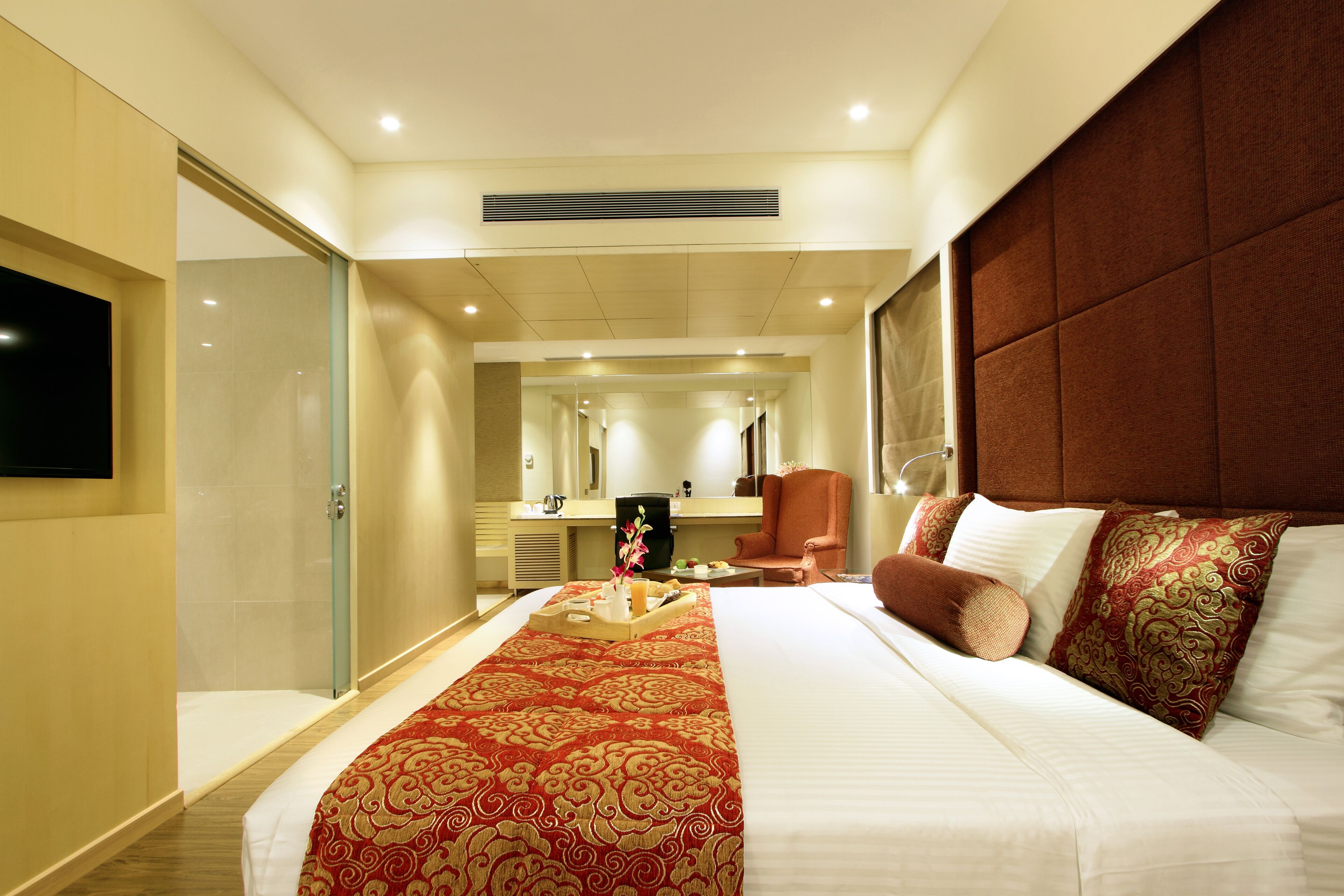 A hotel room with a large bed, a TV, a desk, and a bathroom.