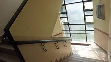 Un escalier muni d’une rampe et une fenêtre donnant sur un paysage verdoyant.