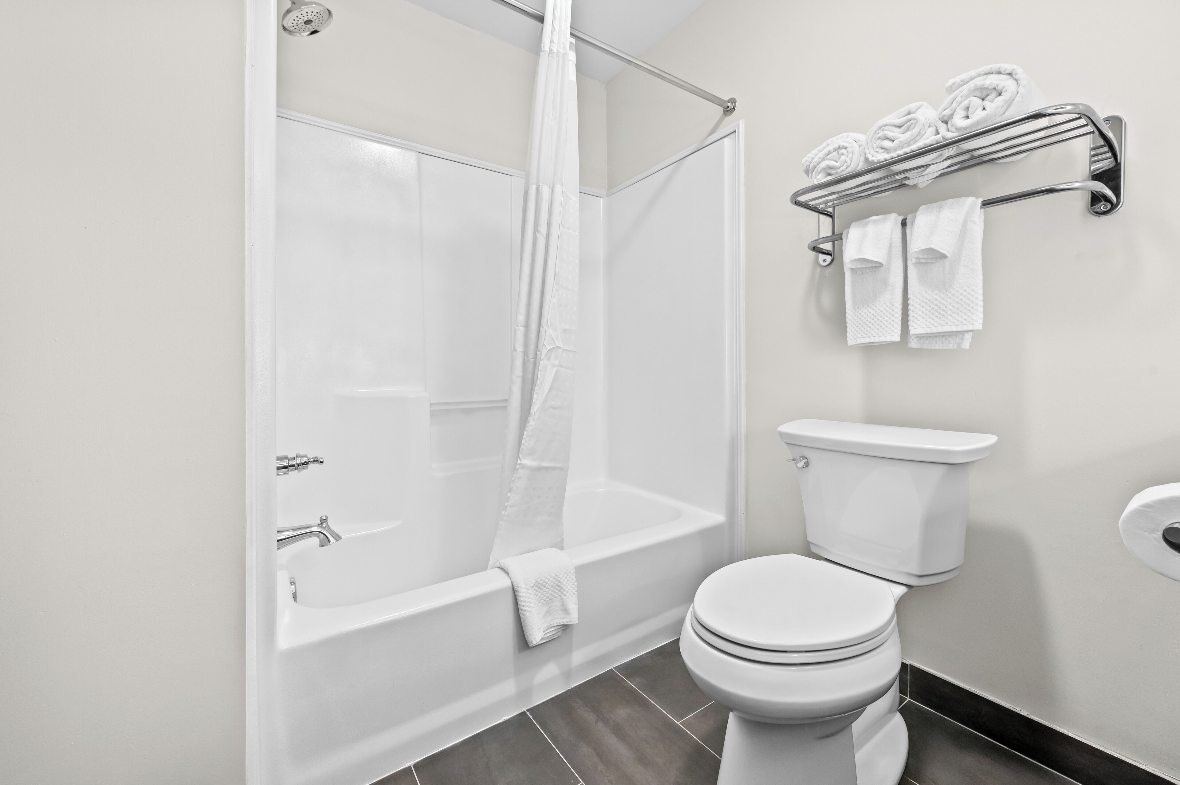 A modern bathroom with a bathtub, toilet, and a towel rack.