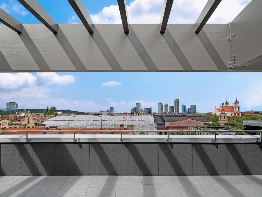 Terraza en la azotea con vistas a un horizonte urbano, que incluye edificios modernos y una iglesia histórica.