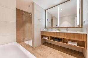 Bathroom features a large mirror, wooden vanity, and a glass-enclosed shower area with a bathtub.