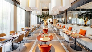 Un espace de restauration moderne avec de longues tables, des chaises et des luminaires suspendus.