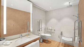 A modern bathroom with a large mirror, two sinks, a shower, and a toilet.