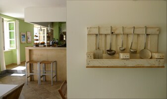 A kitchen with a bar area, stools, and hanging kitchen utensils.
