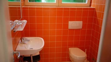 A bathroom with orange tiles, a white sink, and a toilet.