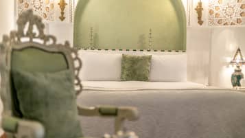 A bed with a green headboard, white bedding, and a decorative pillow.