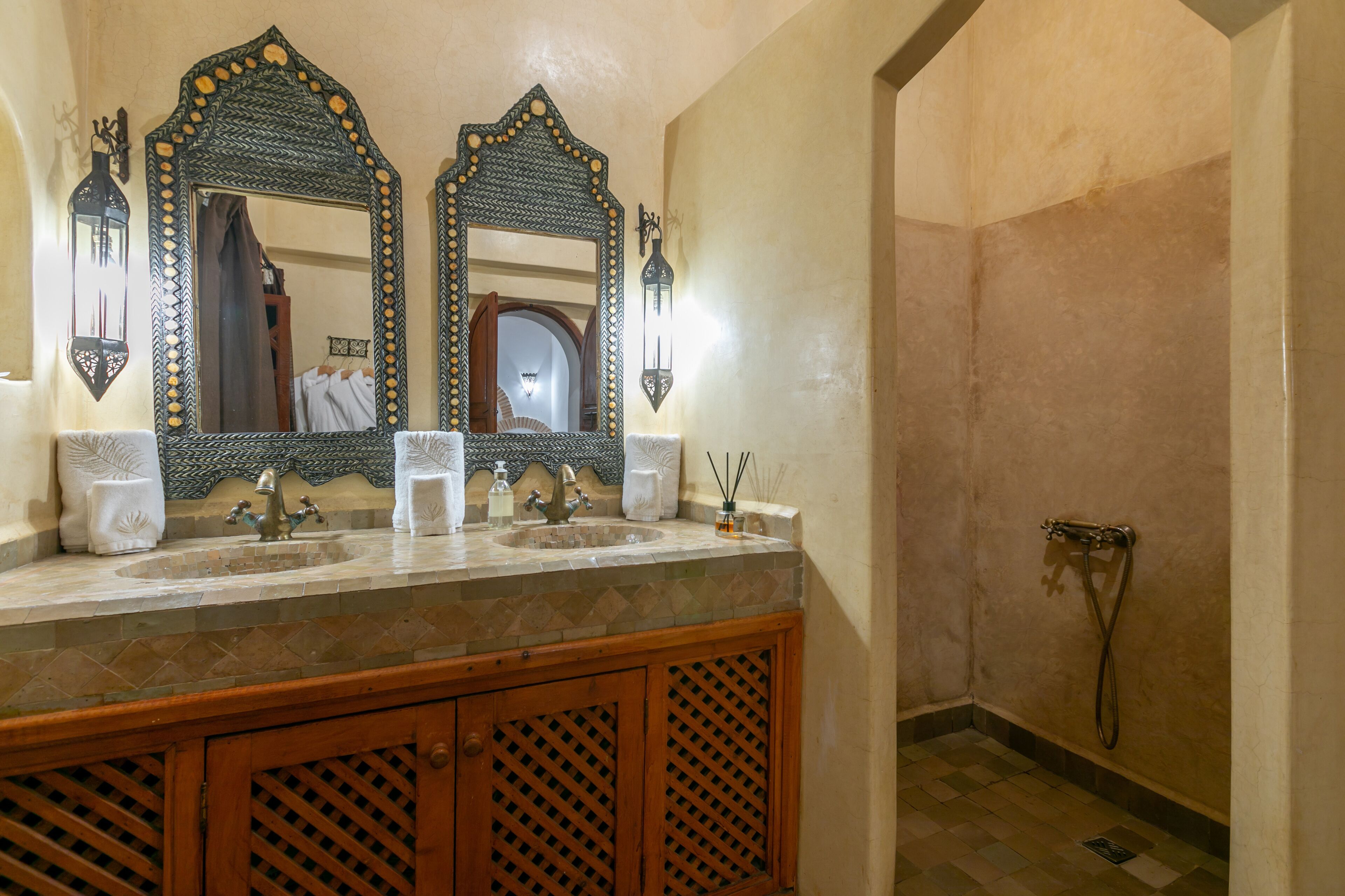 A bathroom with two mirrors, a sink with two faucets, and a shower area.