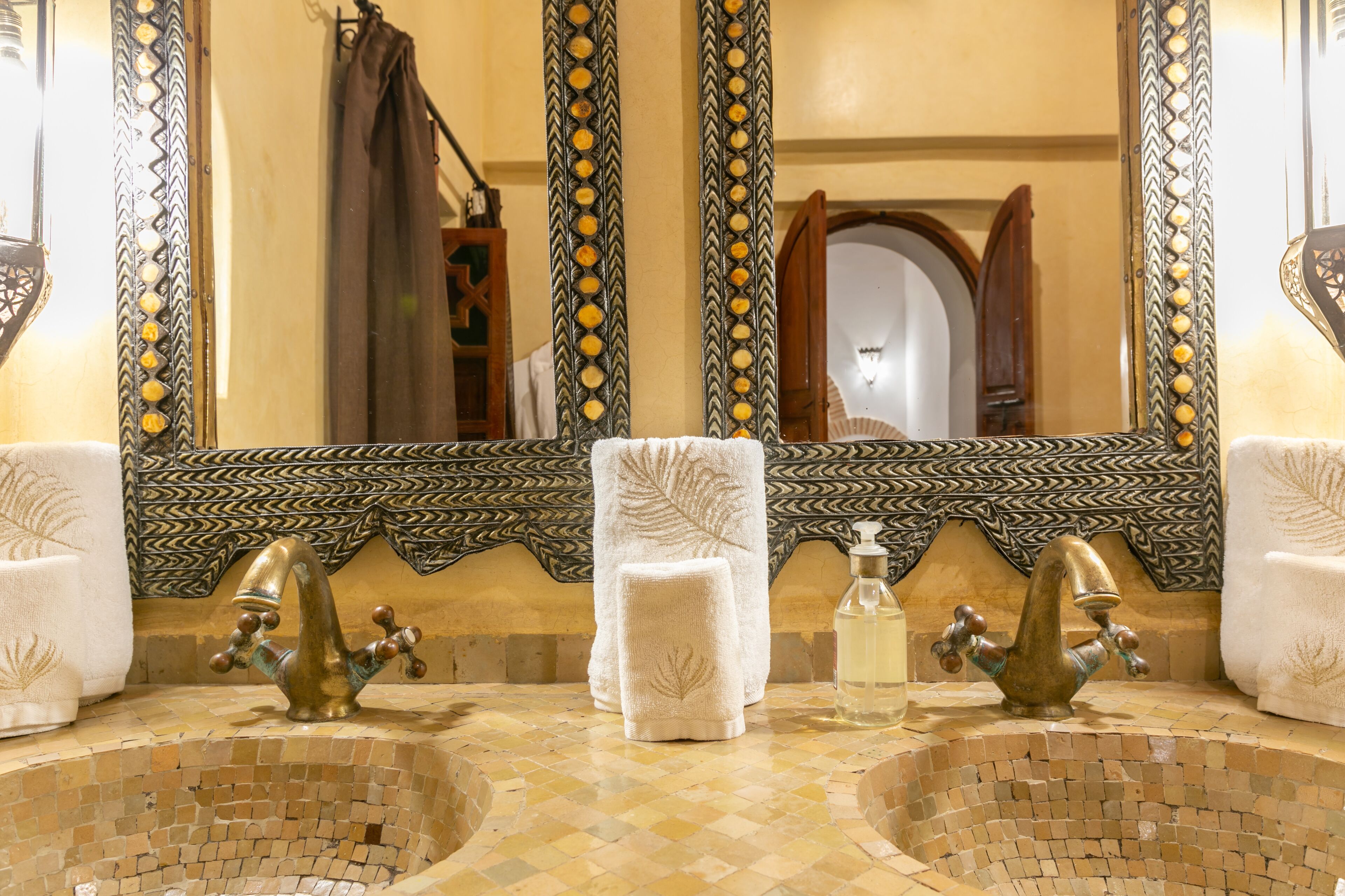 Une salle de bain avec deux lavabos, un grand miroir et des carreaux décoratifs.
