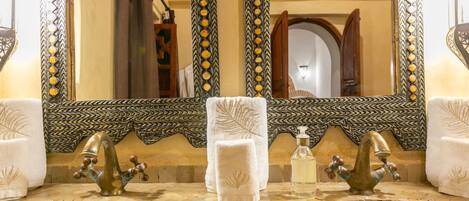 Une salle de bain avec deux lavabos, un grand miroir et des carreaux décoratifs.