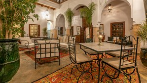 Un interior espacioso con techo alto, arcos ornamentales y un área de comedor central con mesa y sillas.