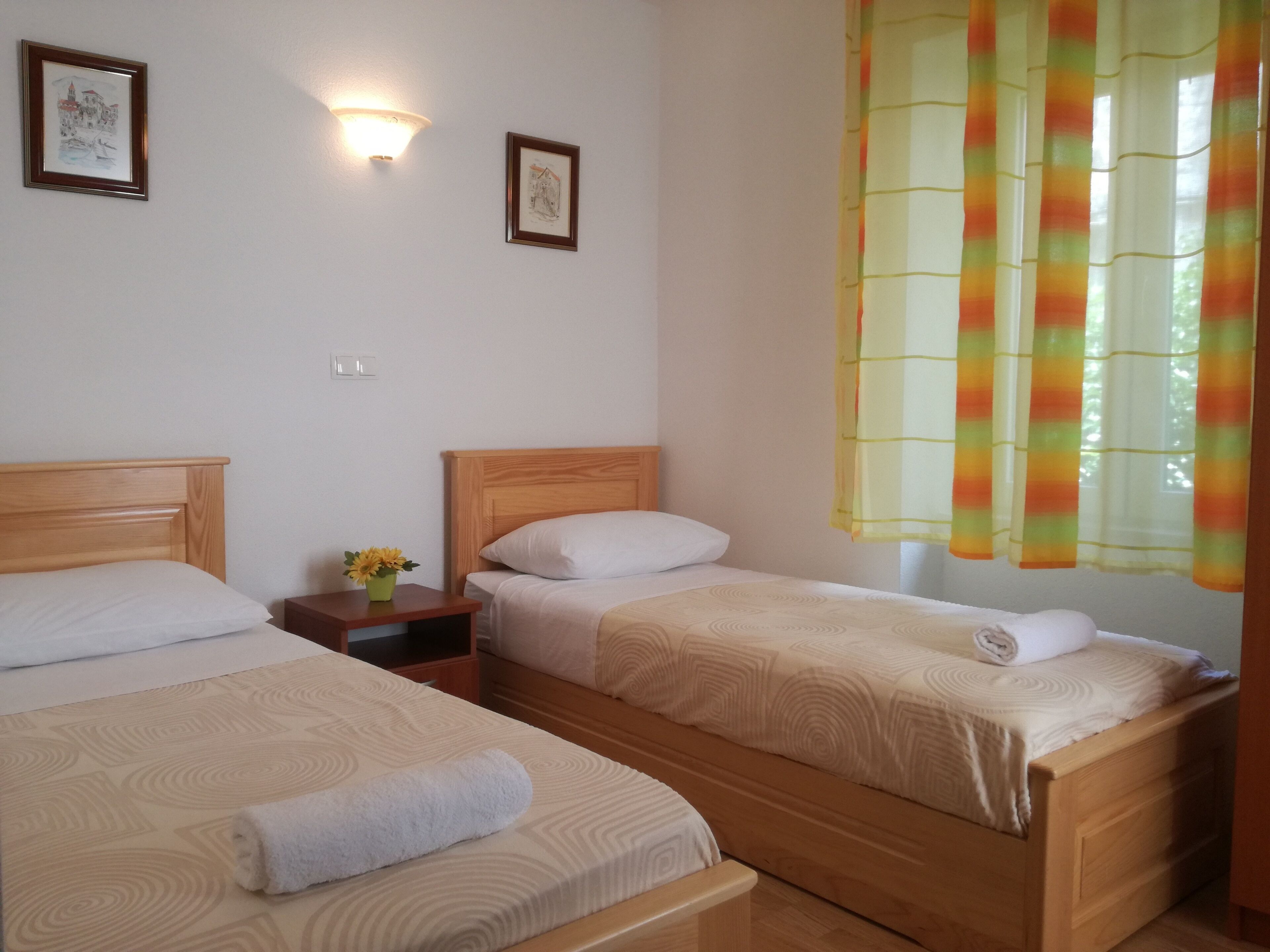 Une chambre d’hôtel avec deux lits, une table de chevet ornée d’un vase de fleurs et deux appliques murales.