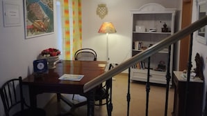A dining area with a wooden table, chairs, a lamp, and a staircase. - Guesthouse Ruzica (Trogir)