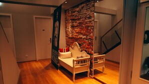 Habitació amb sòl de fusta, un sofà blanc, una paret d'accent de maó i una escala.
