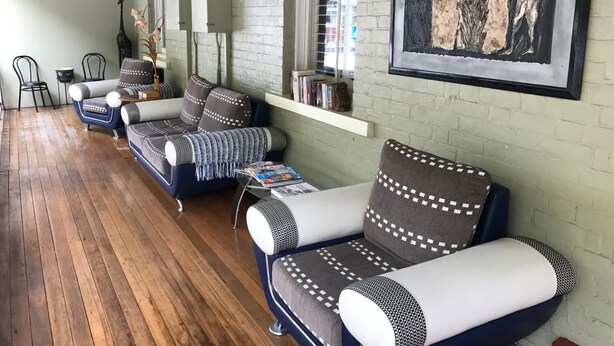 A modern living room with a sofa set, a bookshelf, and a framed artwork on the wall.