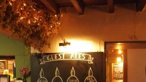 A bar area with a sign reading "GUEST ALES" and four beer taps labeled "BEER," "BEER," "BEER," and "BEER." There are two wooden chairs in front of the bar. - Black Swan Inn (Ripon)