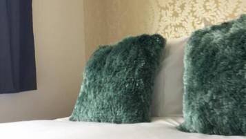 A bed with white bedding and two green pillows.