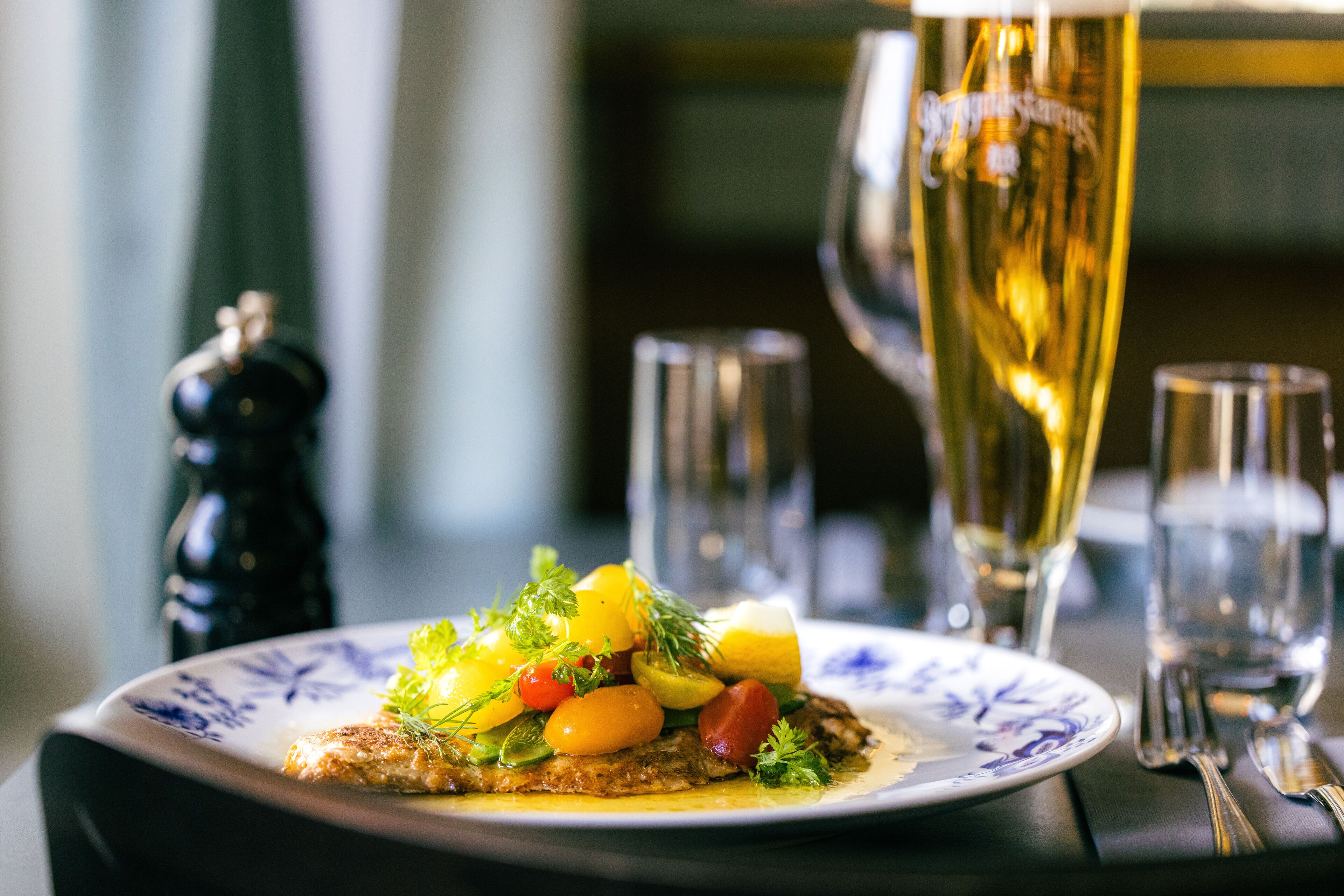 Une assiette de nourriture et un verre de bière sur la table.