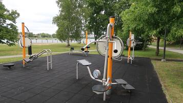 Outdoor exercise equipment in a park with a paved area.