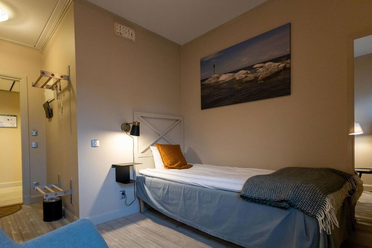 Un dormitorio con cama, lámpara de noche y un cuadro en la pared.
