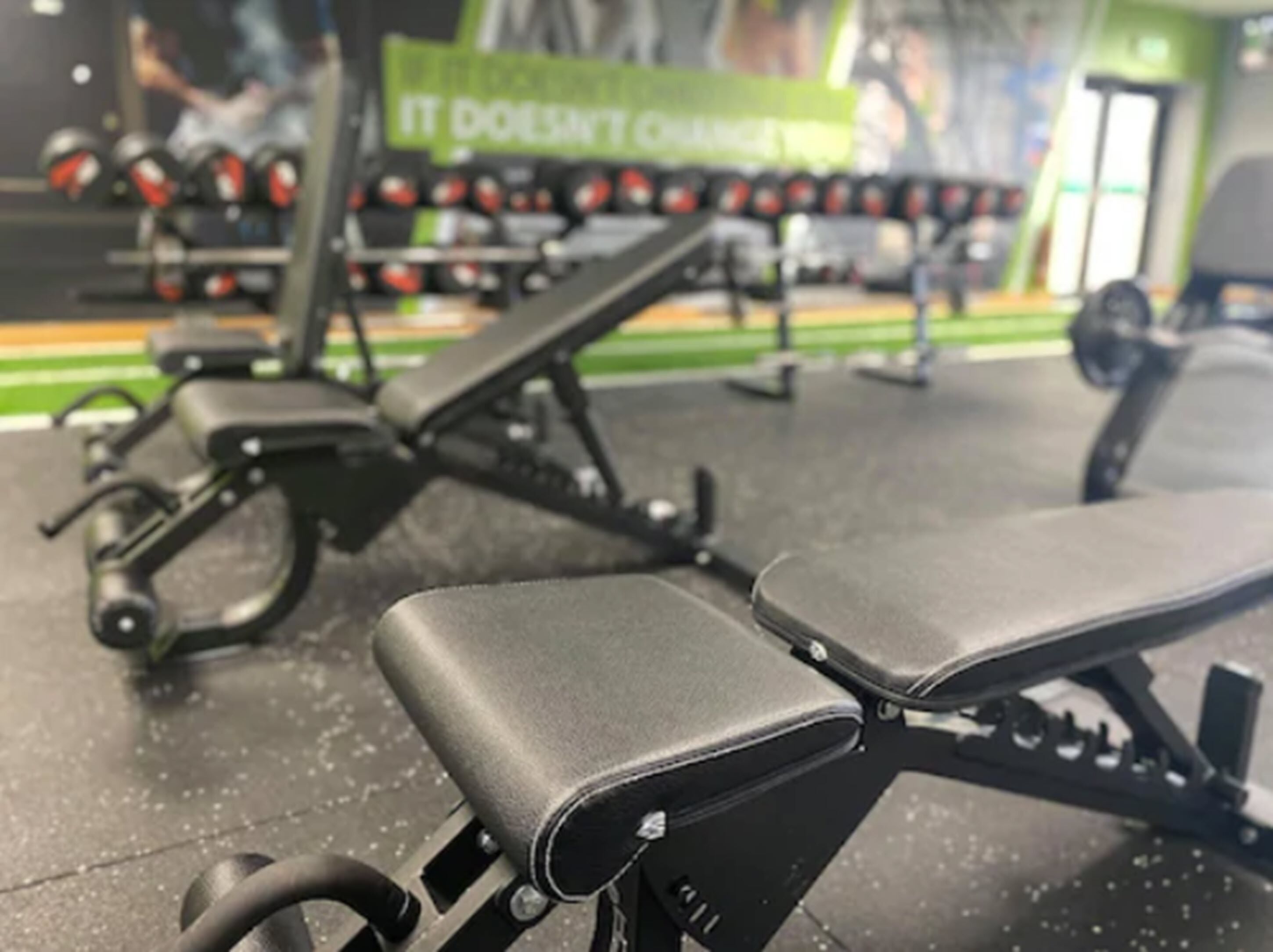Une salle de sport équipée de matériel d’exercice, notamment des bancs et des poids.