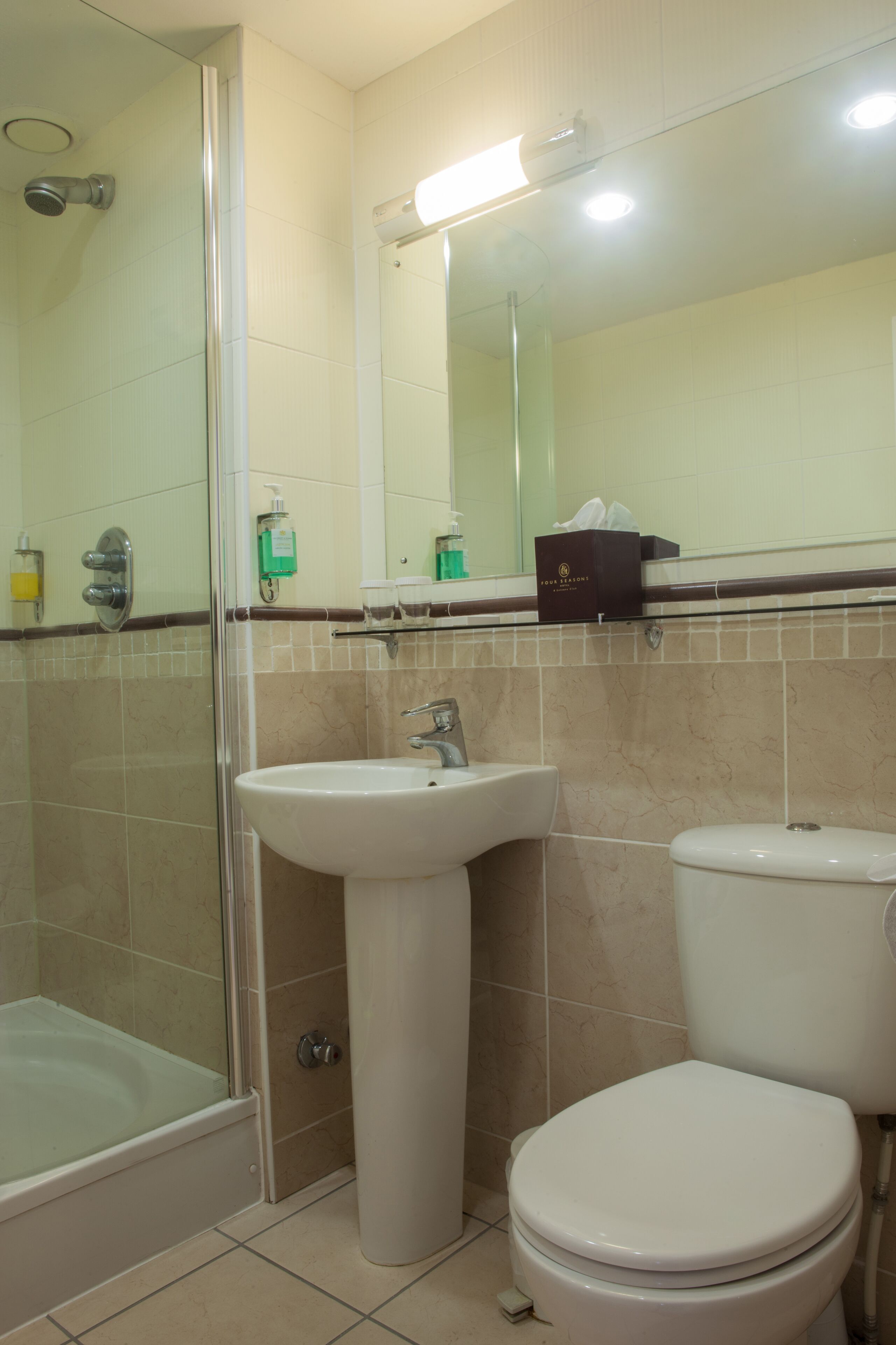 Ein Badezimmer mit Duschkabine, Waschbecken auf Säule und Toilette.