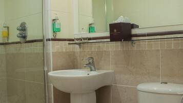 Une salle de bain avec une douche à parois de verre, un lavabo sur colonne et des toilettes.
