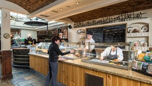A restaurant counter with a menu board above, a chef preparing food, and a customer at the counter. - Four Seasons Hotel & Leisure Club Monaghan (Monaghan)