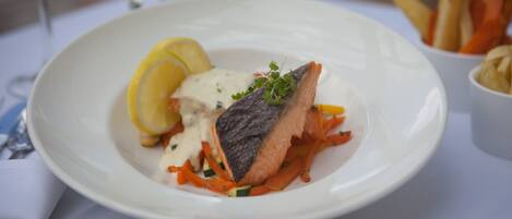 Un plato de comida con salmón, limón y verduras.