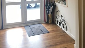 A reception area with a sign above the door, a mat at the entrance, and bicycles against the wall. - Penny Farthing Hotel (Lyndhurst)