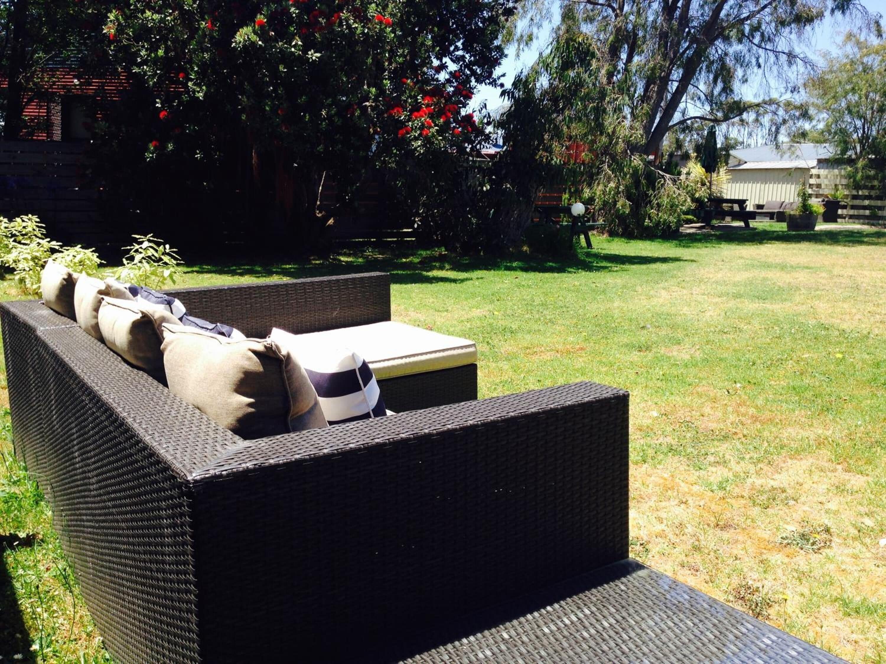 Un sofá de mimbre con cojines en un patio trasero.