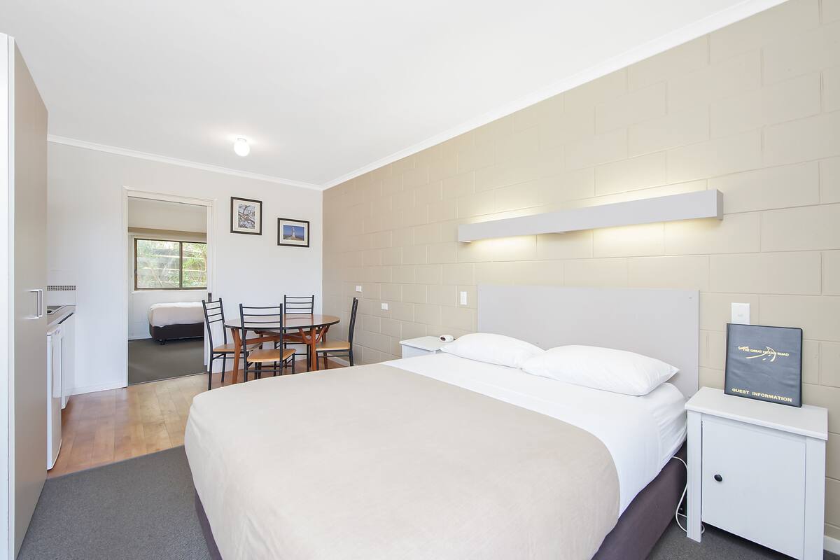 A hotel room with a bed, bedside table, and a desk with chairs.