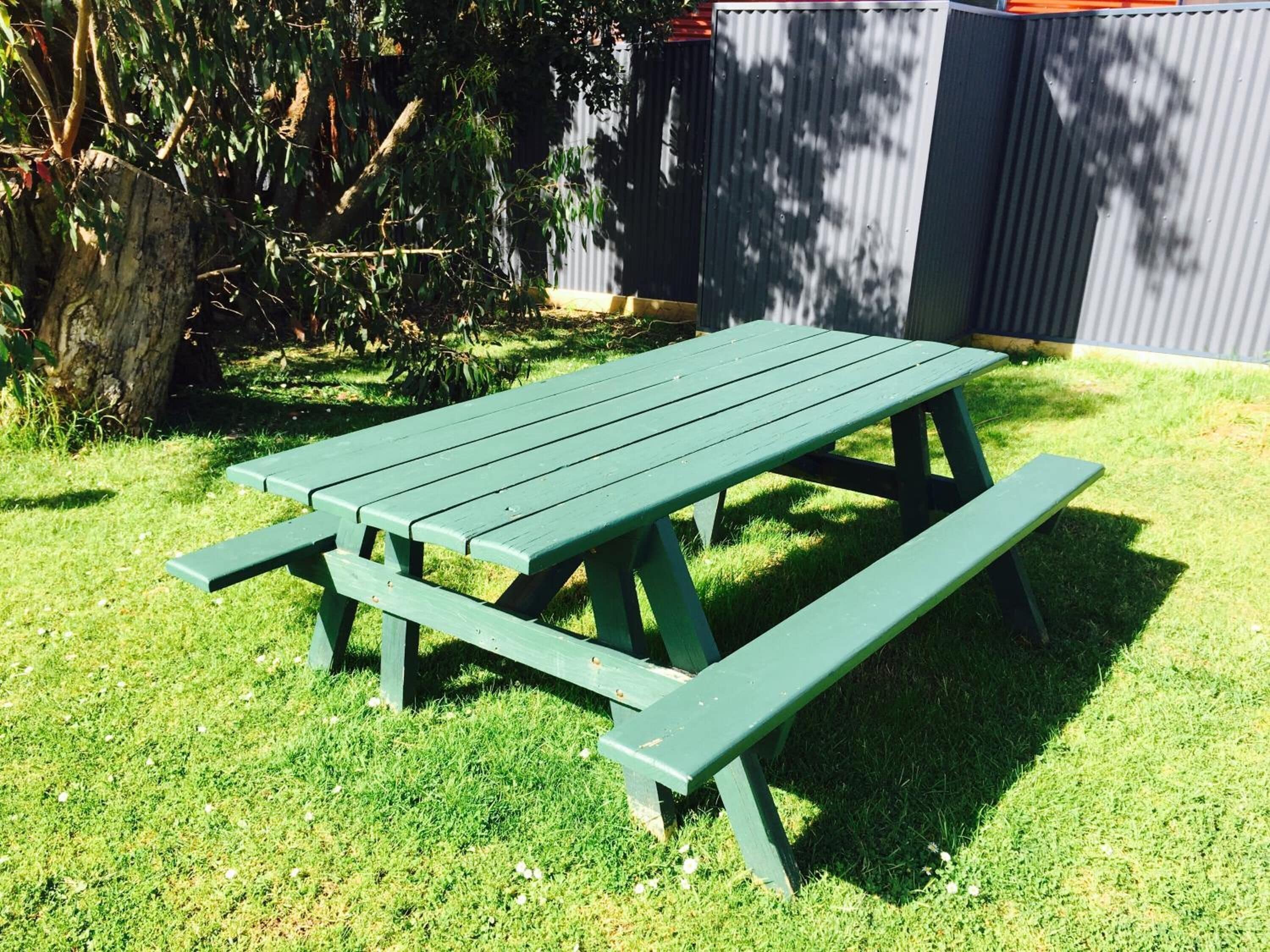 Een groene picknicktafel met bankjes in een gazon.
