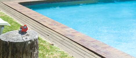 Una piscina con muelle de madera y una silla blanca al fondo.