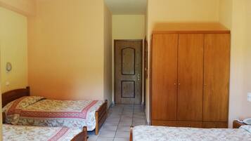 Un dormitorio con dos camas individuales, un armario y una puerta que da a otra habitación.