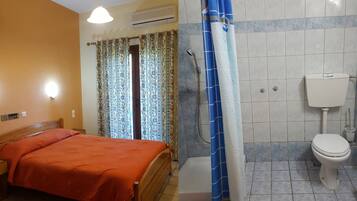 Een slaapkamer met een bed, douche en toilet.