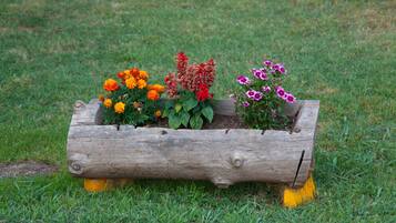 Un bac à fleurs en bois, orné de différentes variétés de fleurs, est posé sur une pelouse verdoyante.