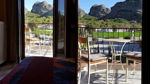 A room with a large window overlooking a balcony with chairs and a view of mountains. - Spanias (Kalabaka)