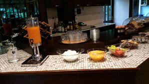A buffet setup with various food items and a juice dispenser. - Spanias (Kalabaka)