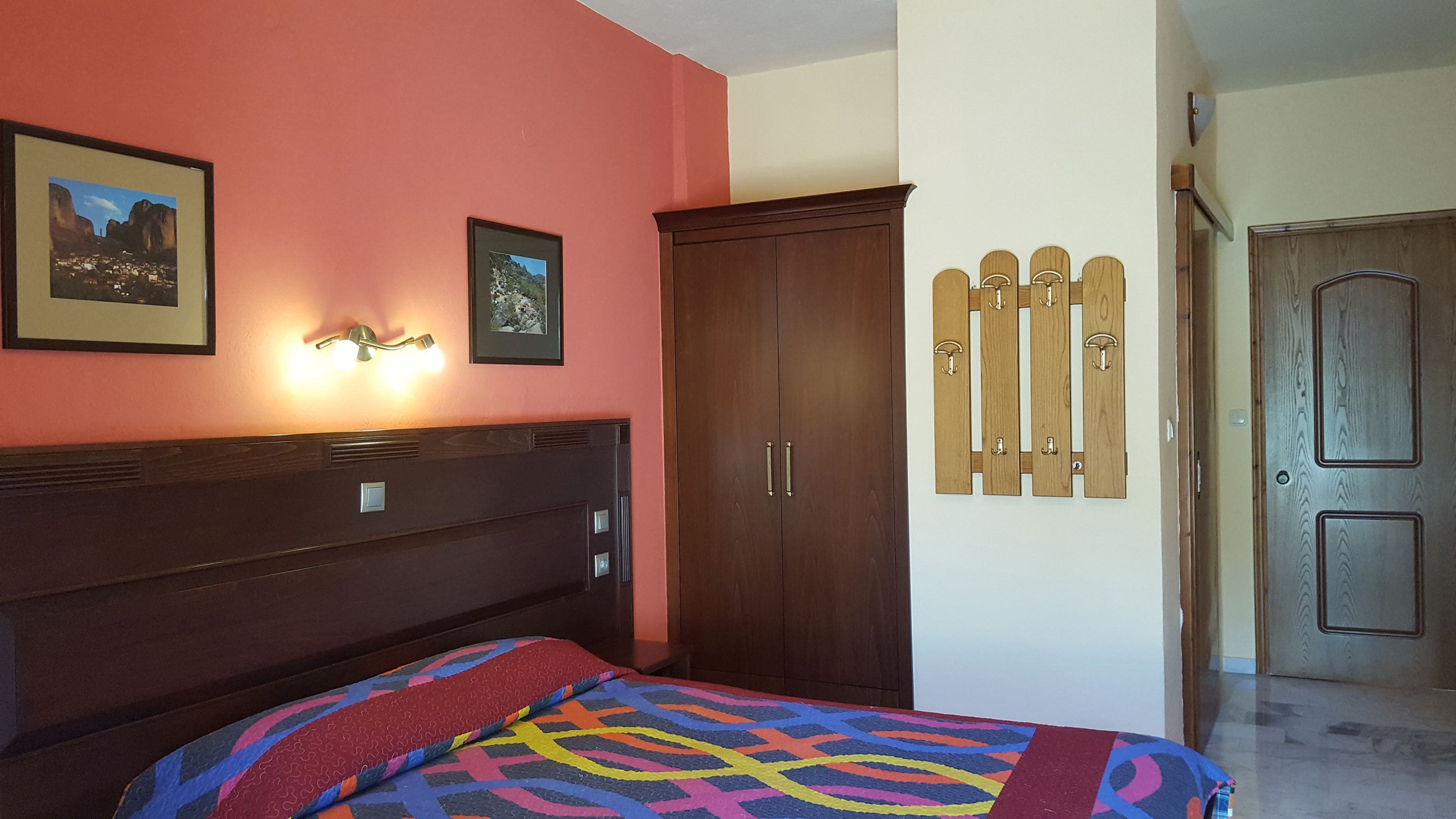 Un dormitorio con una cama, un armario y dos cuadros en la pared.
