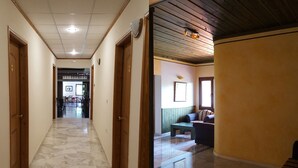 A hallway with marble flooring leading to a room with a wooden ceiling and a window. - Spanias (Kalabaka)