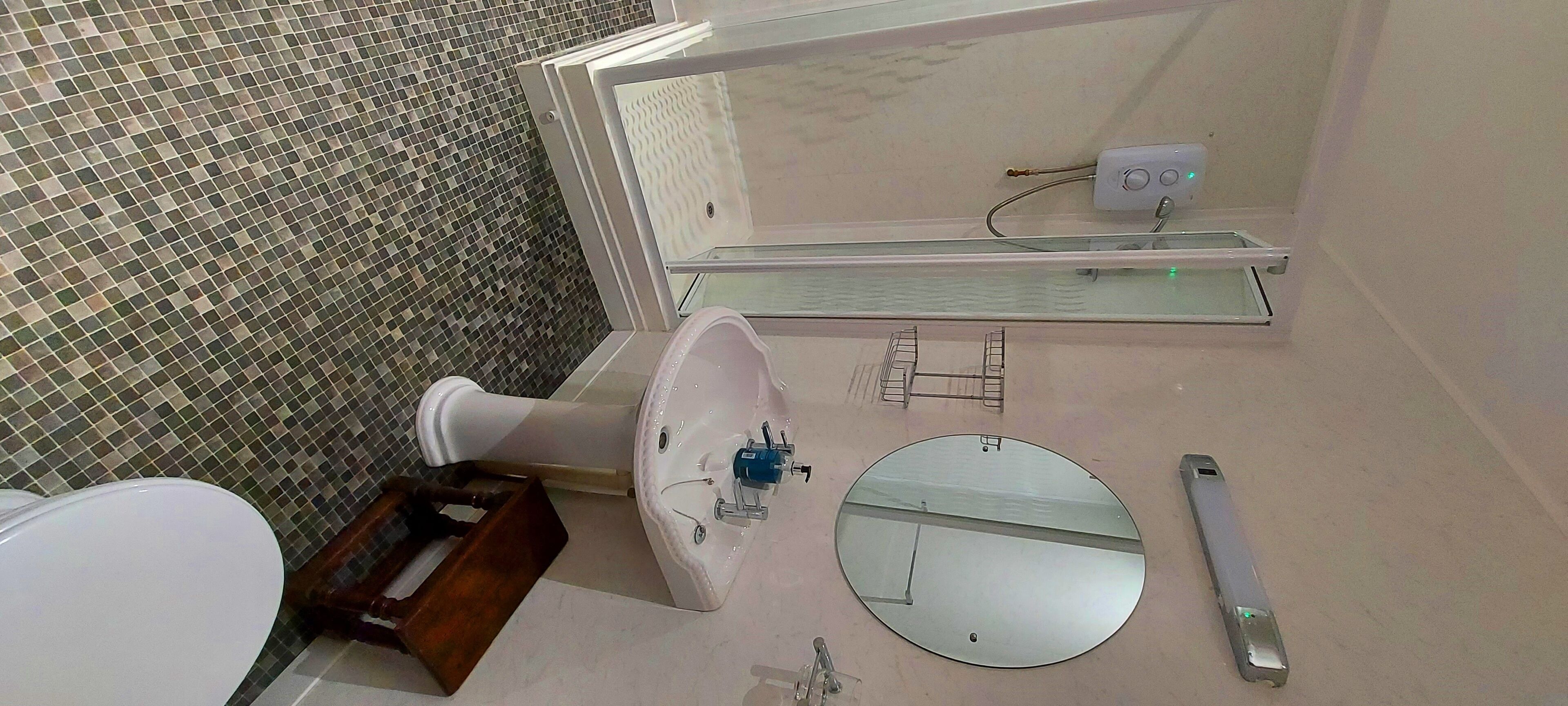 Un bagno con il water, un lavandino, uno specchio e un piccolo ripiano con articoli da toilette.