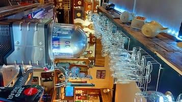 A bar area with a large beer tap, multiple wine glasses, and a variety of bottles and bottles.