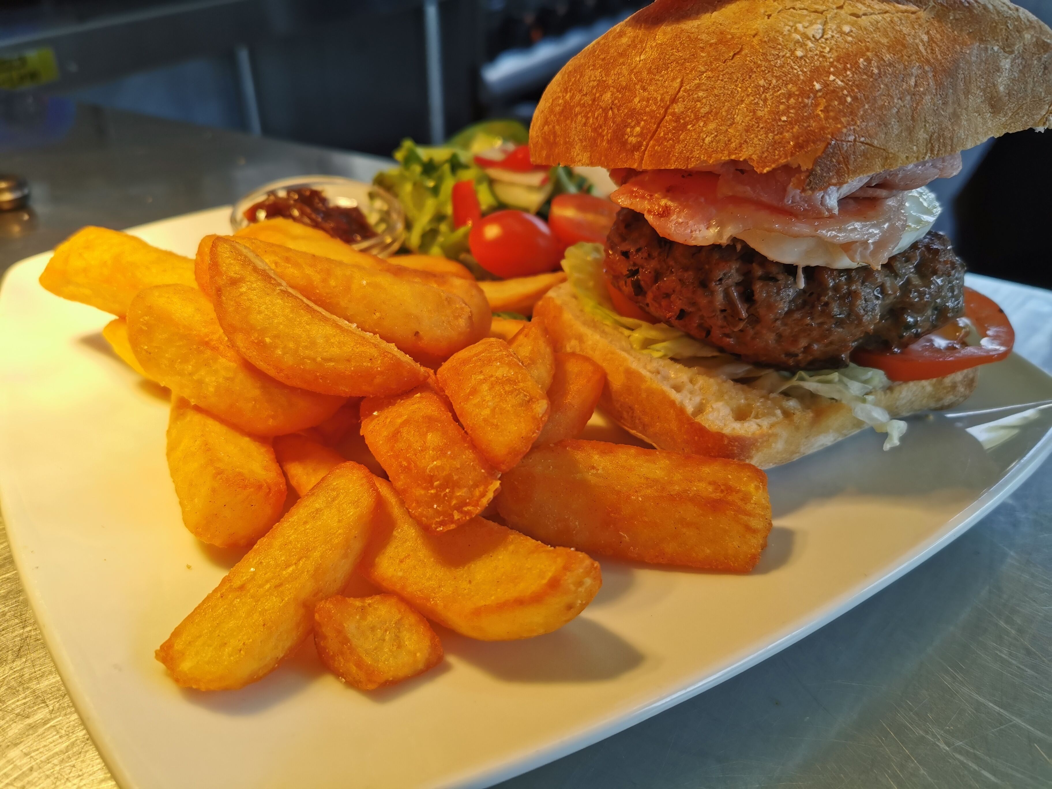 A plate with a burger, fries, and a side salad.