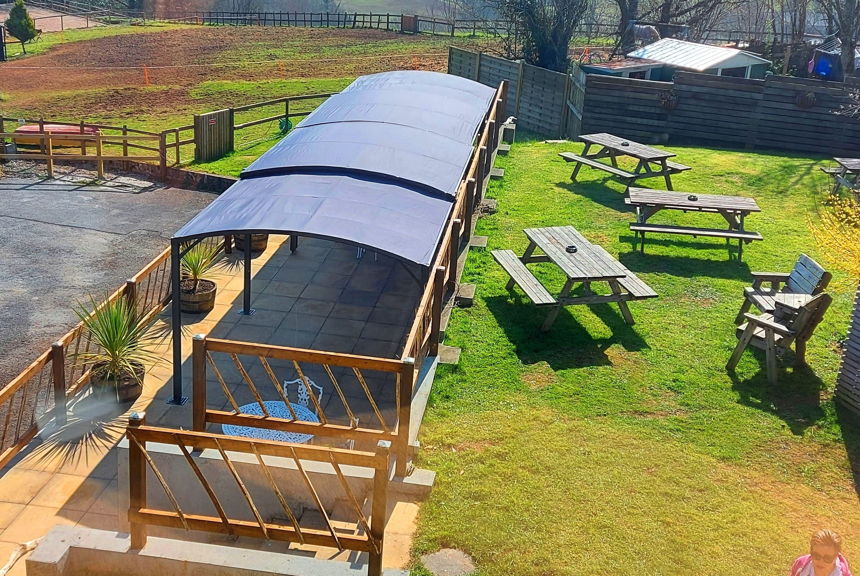 Un espacio de estar al aire libre cubierto con mesas de picnic y una terraza de madera.