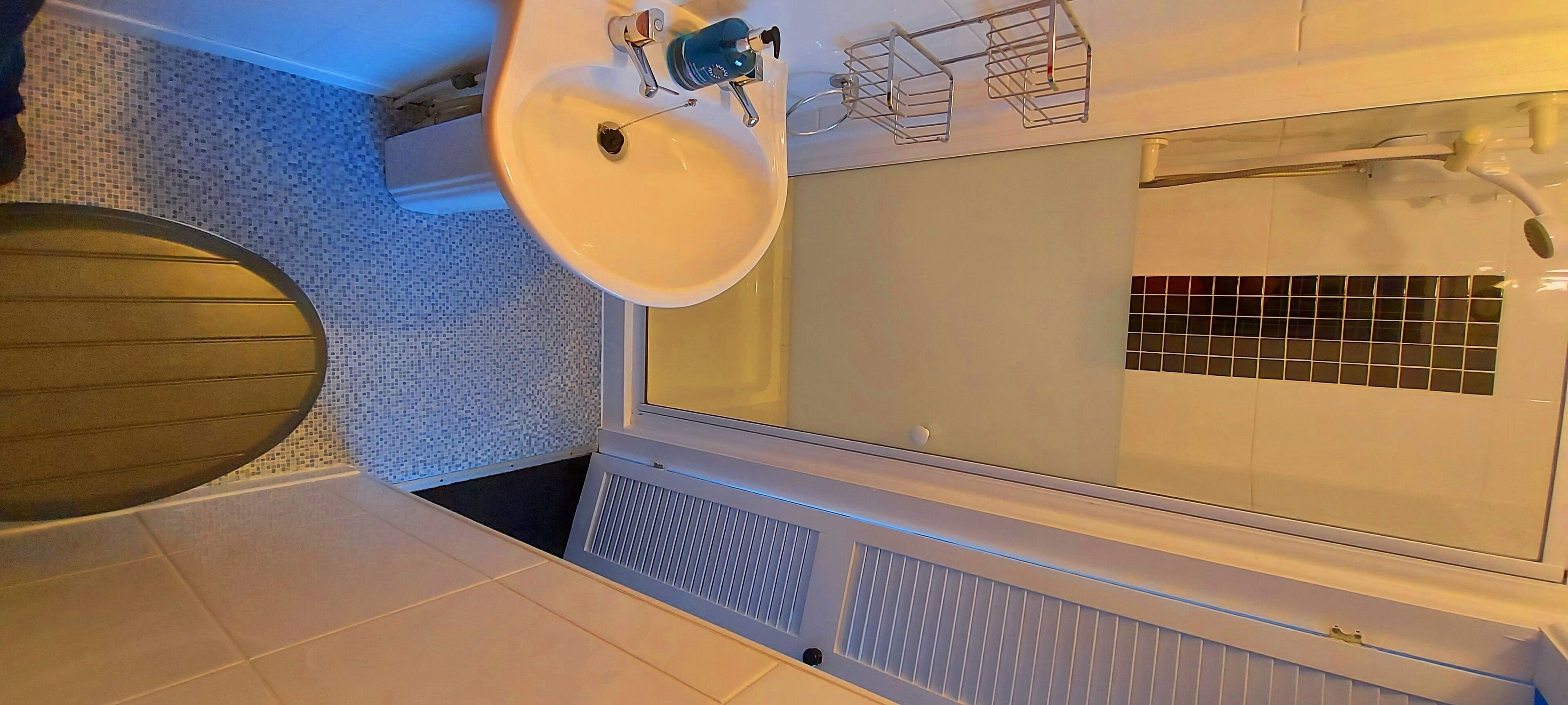 Un baño con lavamanos blanco, un espejo y una ducha.