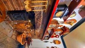 A room with a rustic interior, featuring a stone wall, a wooden door, and a metal chandelier. There is a small table with a basket and a bottle on it. - Sportsmans Valley Hotel (Liskeard)